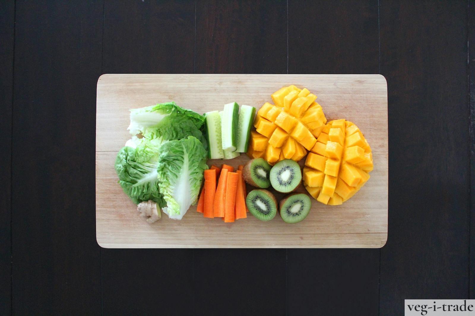 Fresh fruits and vegetables prepared for healthy salad on a wooden chopping board.