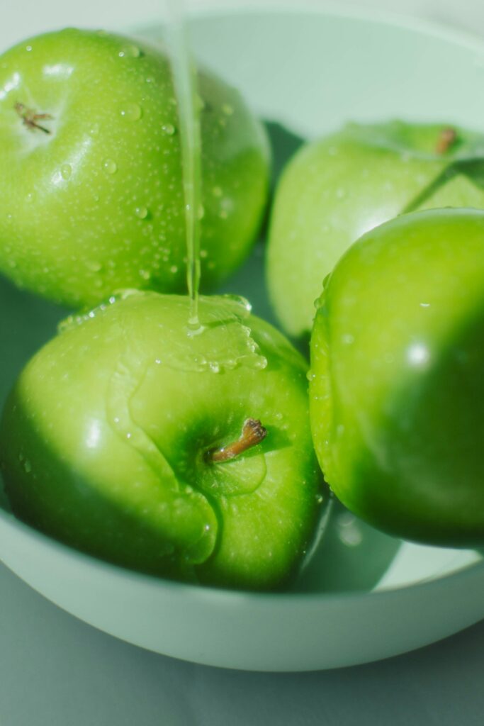 Manzanas verdes en un recipiente con agua para desinfectar frutas y verduras