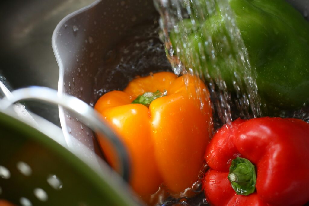 Manojo de verduras frescas lavándose en el fregadero: seguridad alimentaria en casa
